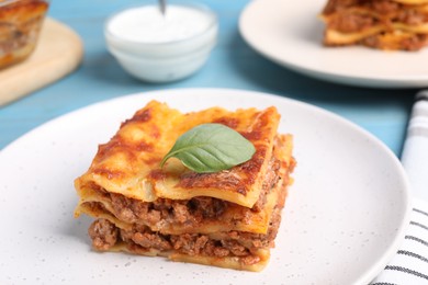 Photo of Tasty cooked lasagna served on light blue table, closeup