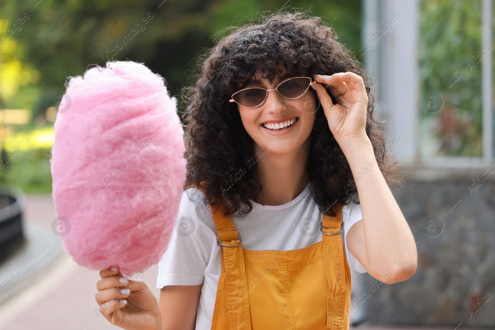 Photo of Portrait of smiling woman with cotton candy in park