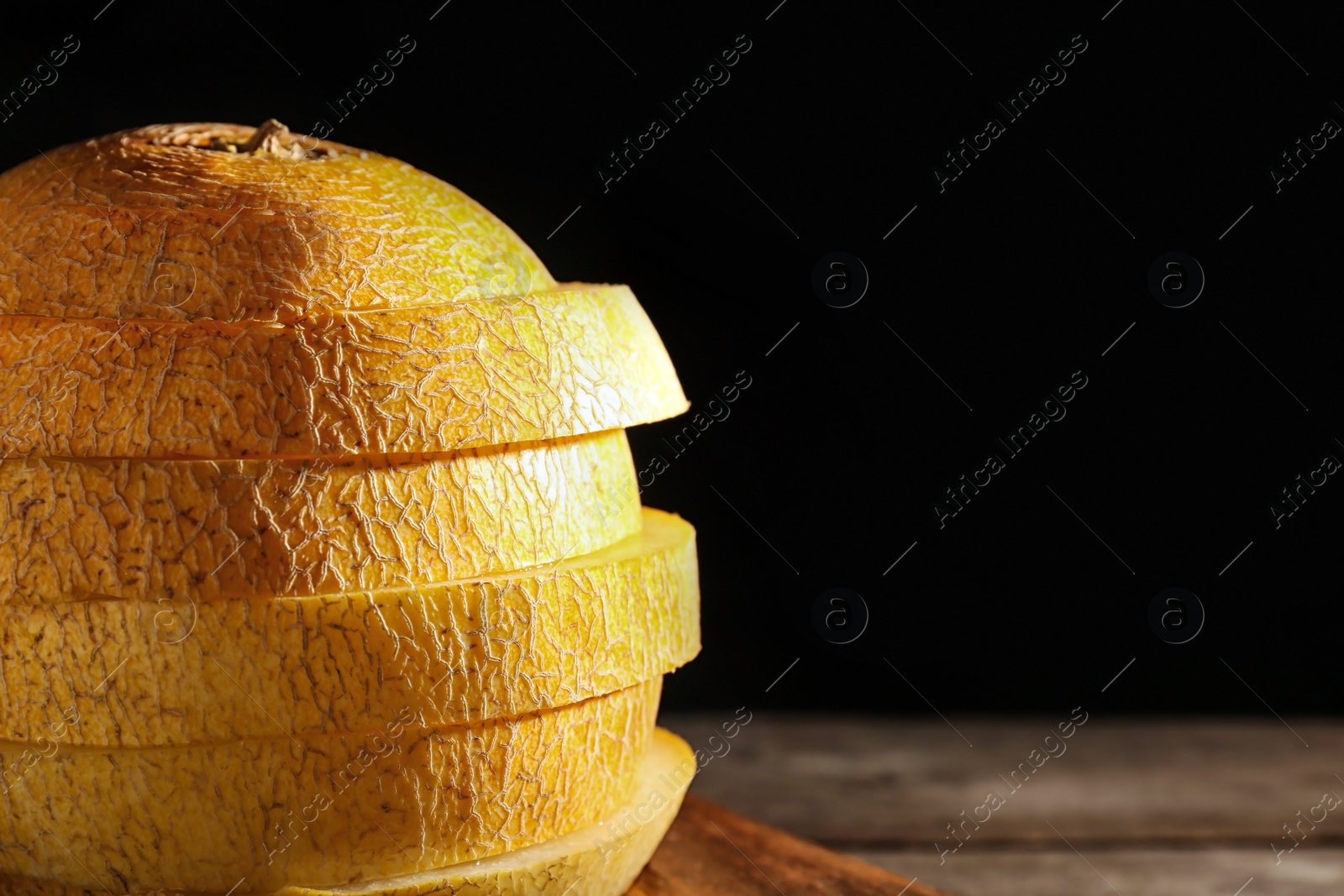 Photo of Sliced ripe melon on table against black background, closeup. Space for text