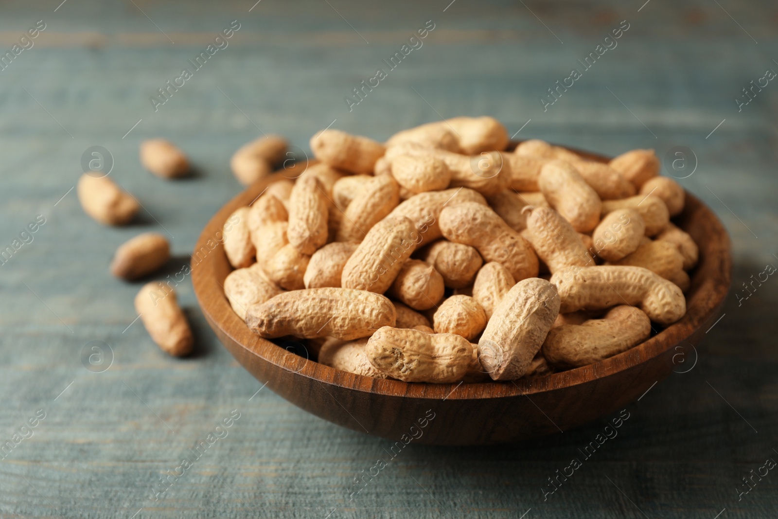Photo of Bowl with peanuts in shell on table