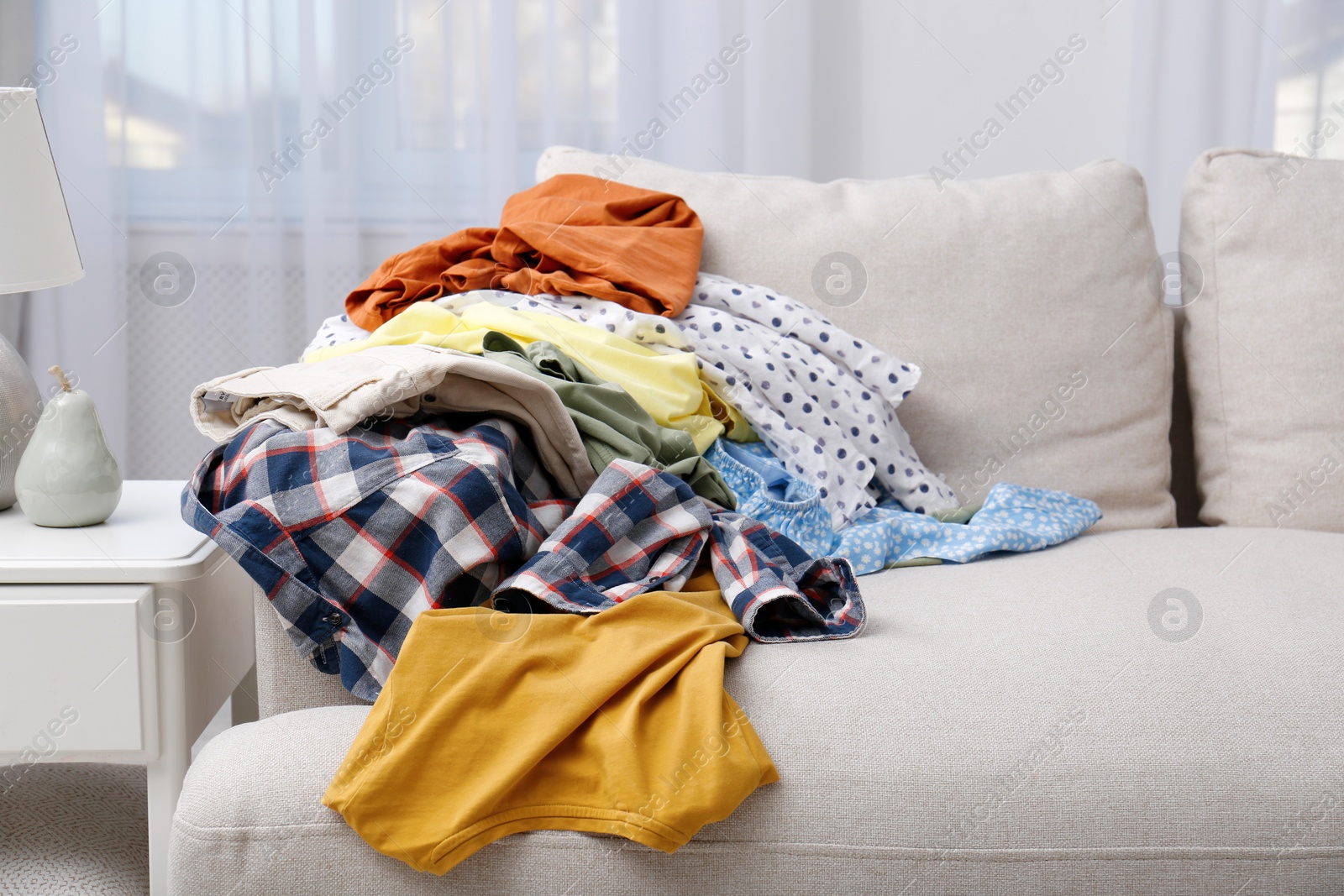 Photo of Messy pile of dirty clothes on sofa in living room. Tidying up method