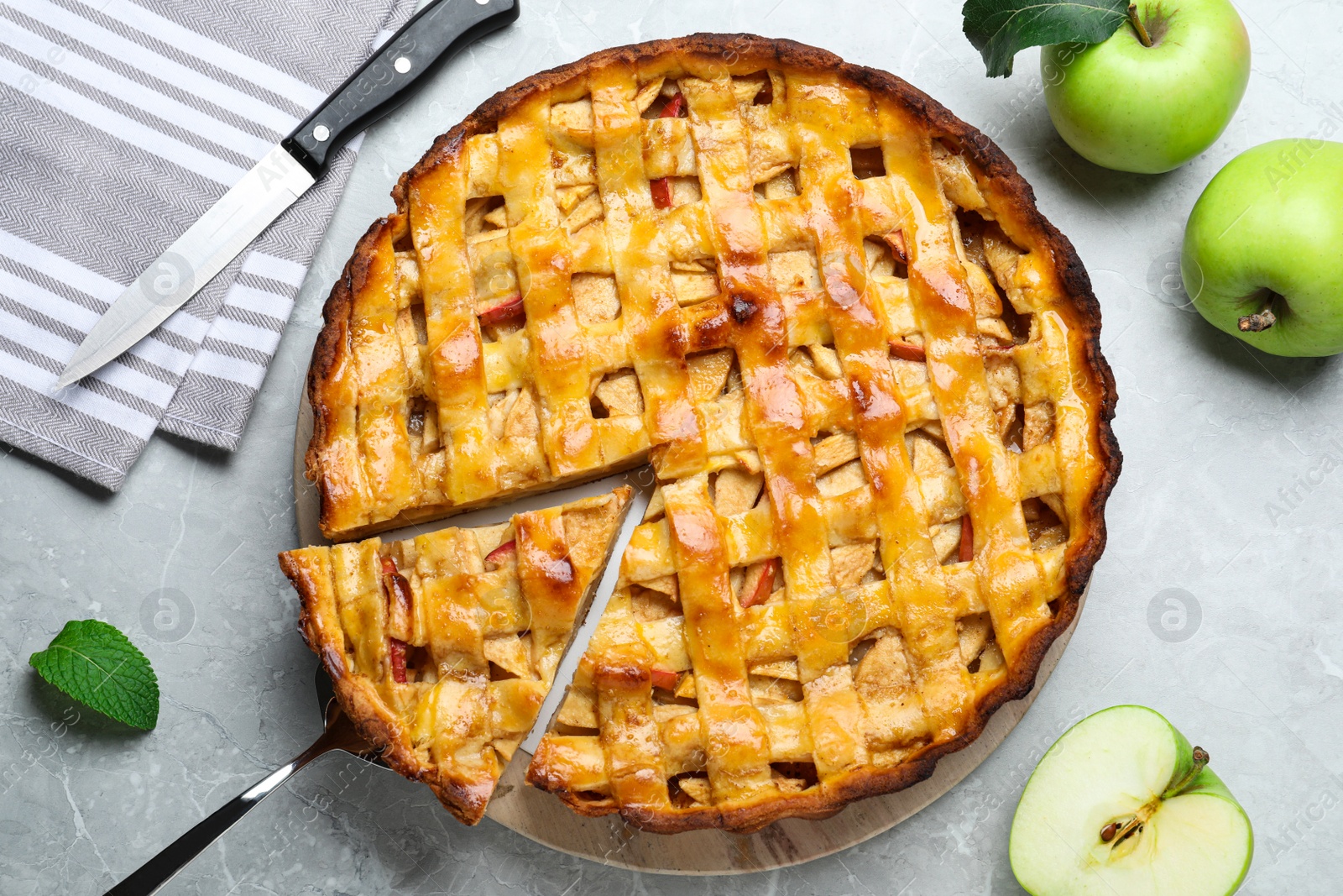 Photo of Fresh traditional apple pie and fruits on light grey table, flat lay