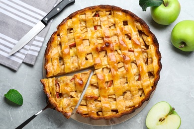 Fresh traditional apple pie and fruits on light grey table, flat lay