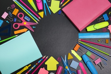 Flat lay composition with different school stationery on chalkboard surface