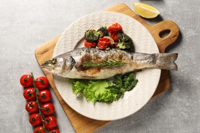 Photo of Delicious baked fish and vegetables on light grey table, top view