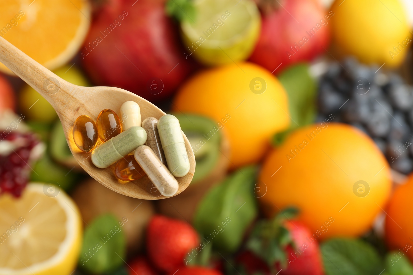 Photo of Different vitamin pills in spoon over fresh fruits, top view. Space for text