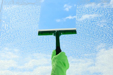 Photo of Woman cleaning glass with squeegee indoors, closeup