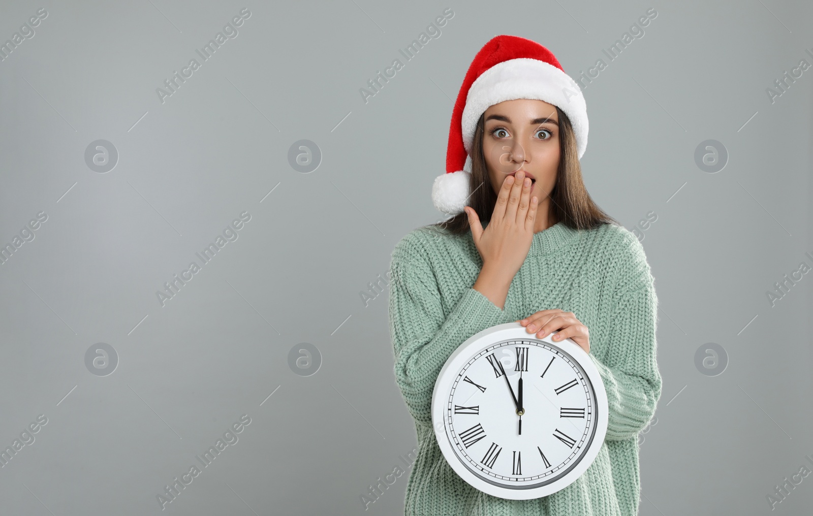 Photo of Woman in Santa hat with clock on grey background, space for text. Christmas countdown
