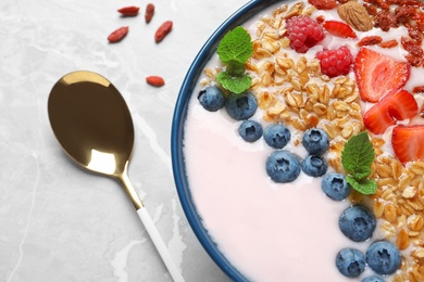 Photo of Smoothie bowl with goji berries and spoon on grey table, closeup