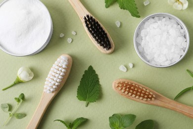 Flat lay composition with toothbrushes and herbs on light olive background