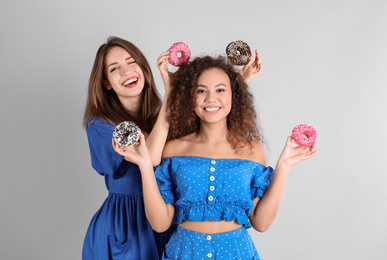 Photo of Beautiful young women with donuts on light grey background
