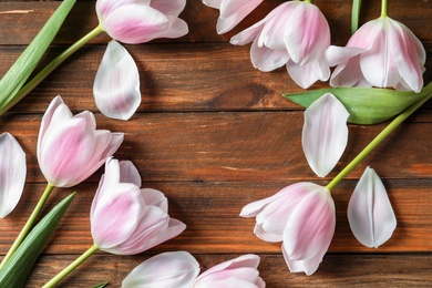 Photo of Beautiful frame made of tulips for Mother's Day on wooden background