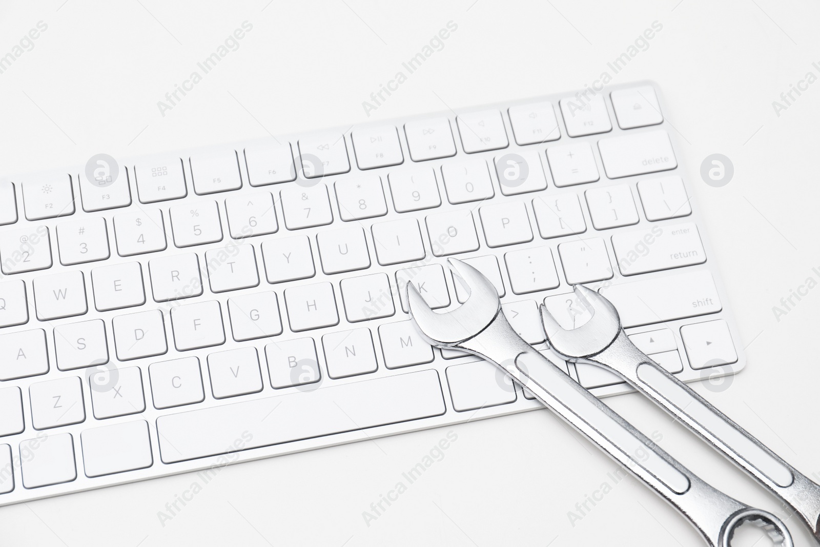 Photo of Wrenches and computer keyboard on light background. Concept of technical support