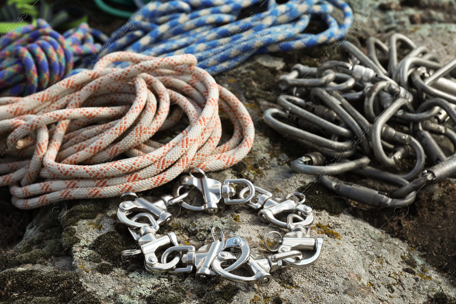 Photo of Different ropes and carabiners on rock, closeup. Climbing equipment