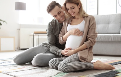 Photo of Young pregnant woman with her husband at home