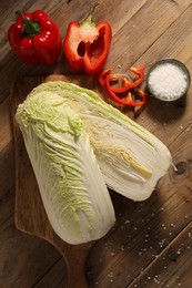 Photo of Fresh Chinese cabbages, bell peppers and salt on wooden table, flat lay