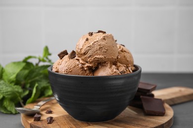 Photo of Bowl with tasty chocolate ice cream on wooden board, closeup