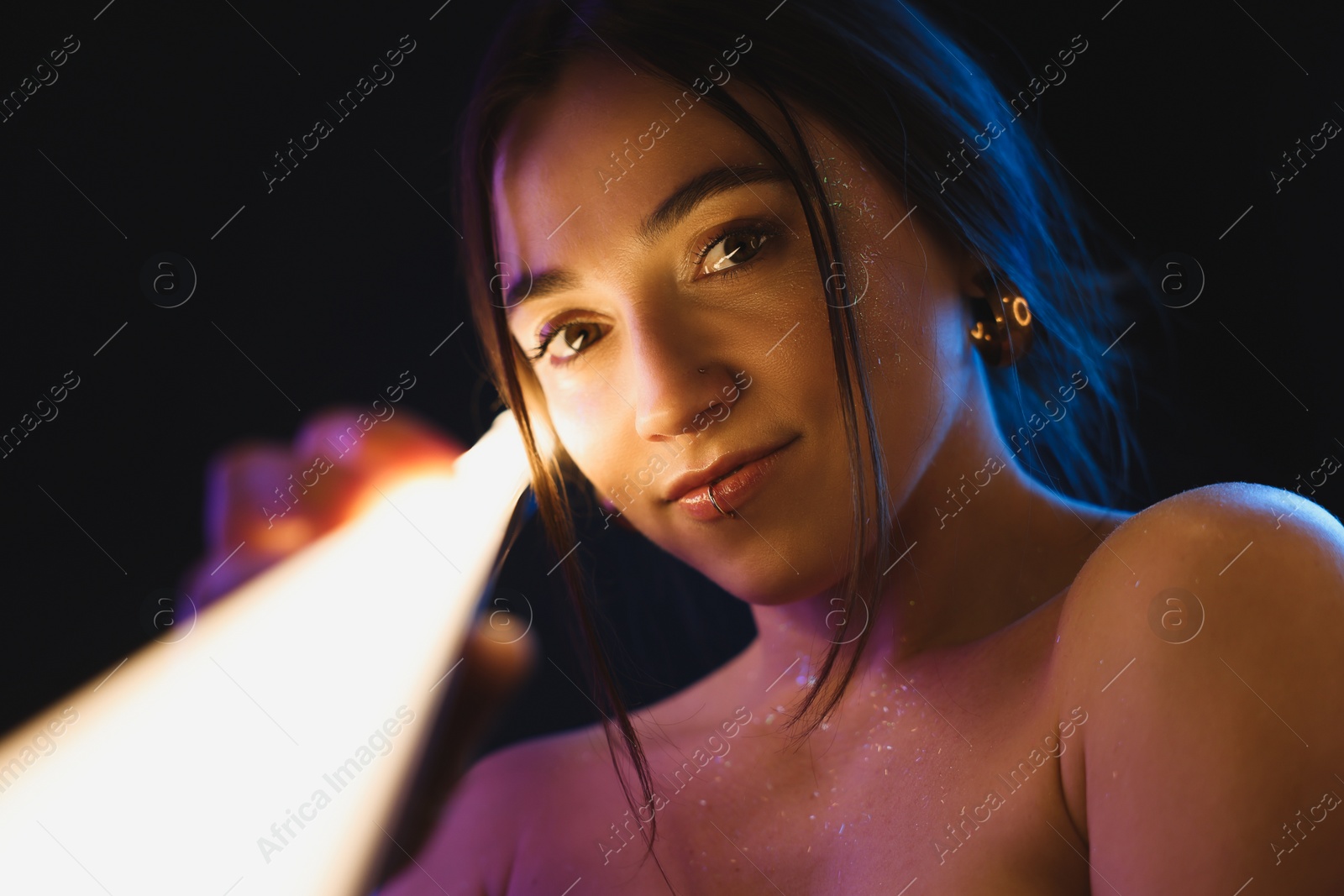 Photo of Beautiful woman with lamp on dark background in neon lights