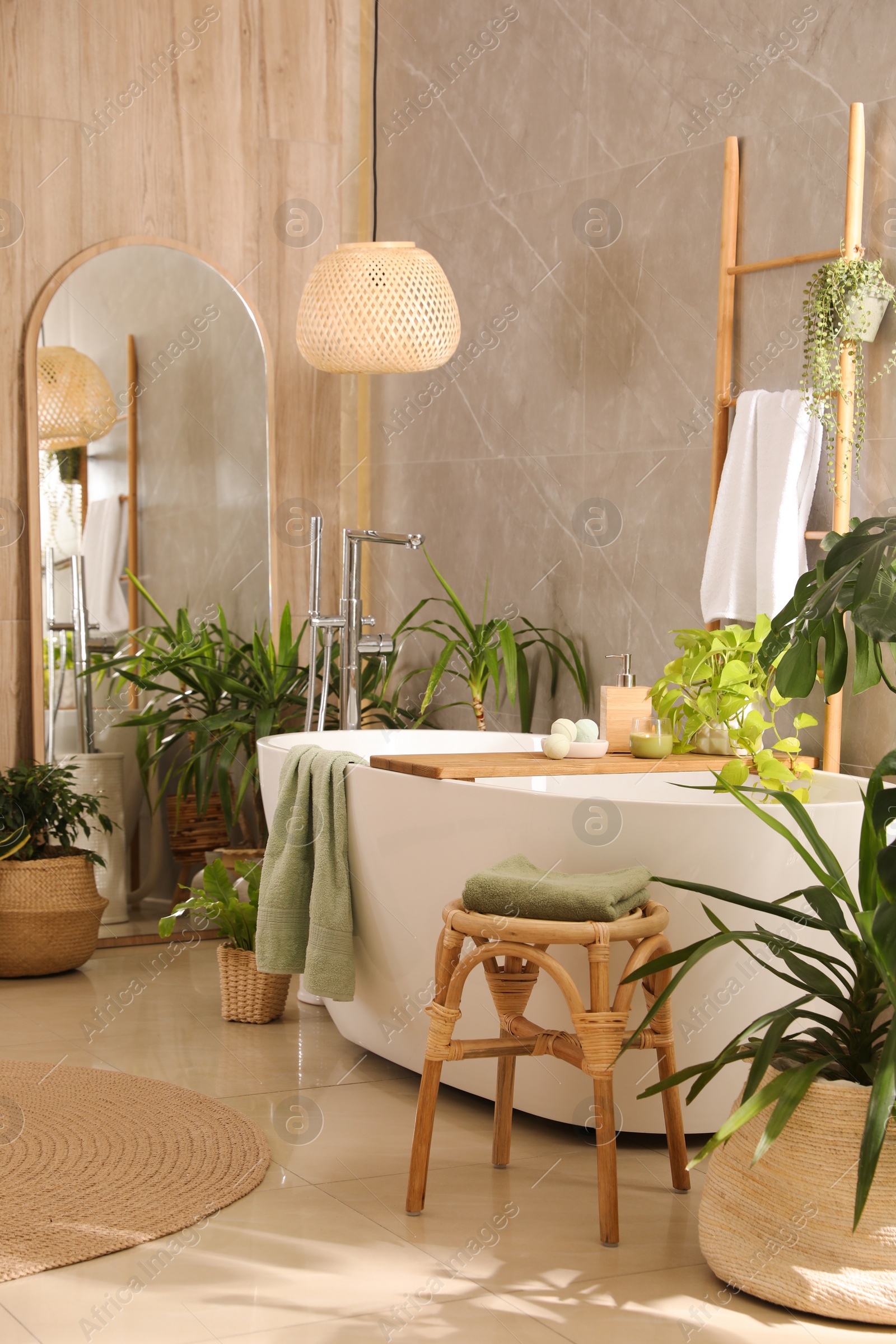 Photo of Modern white tub and beautiful green houseplants in bathroom. Interior design