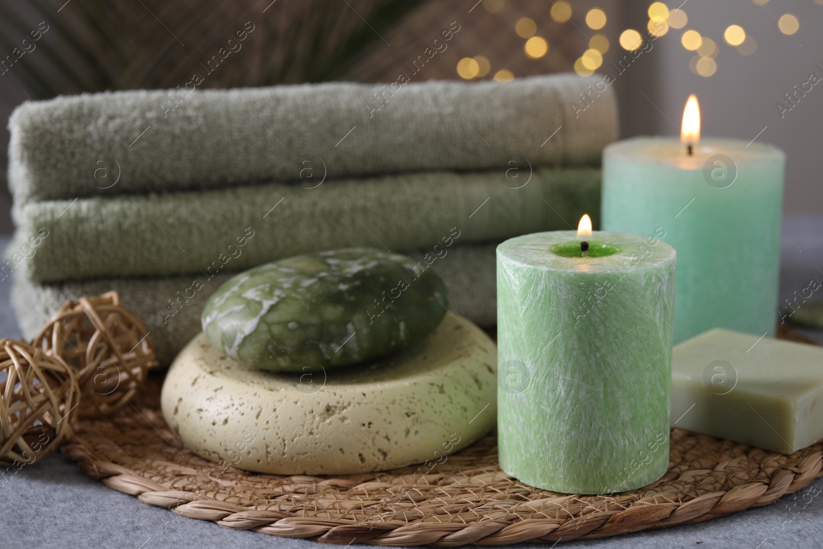 Photo of Spa composition. Burning candles, stone, soap and towels on grey table