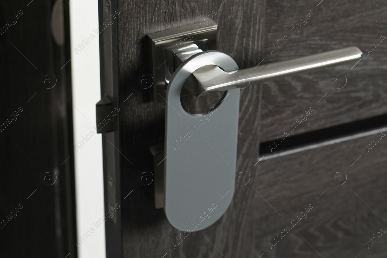 Photo of Wooden door with blank hanger on metal handle, closeup