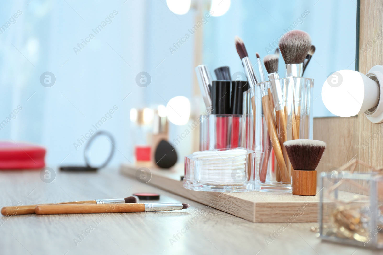 Photo of Organizer with cosmetic products for makeup on table near mirror. Space for text