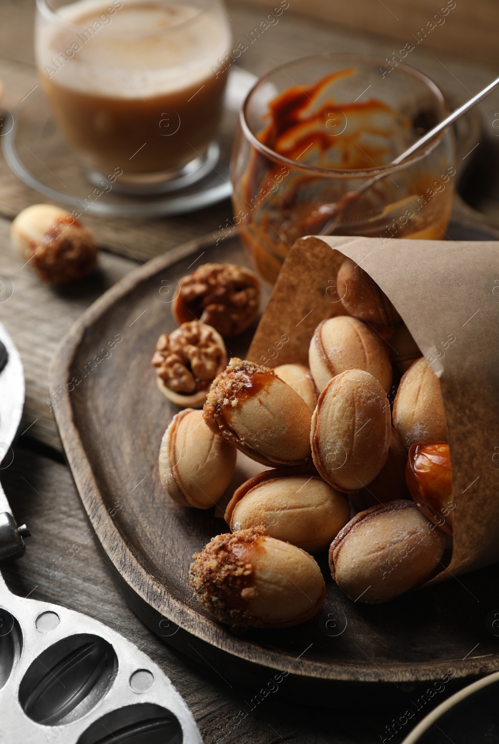 Photo of Freshly baked homemade walnut shaped cookies and boiled condensed milk on wooden table