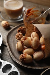 Photo of Freshly baked homemade walnut shaped cookies and boiled condensed milk on wooden table