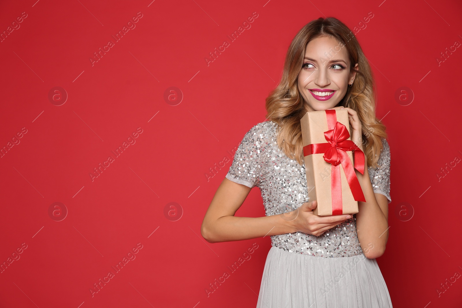Photo of Happy woman with gift box on red background, space for text. Christmas party