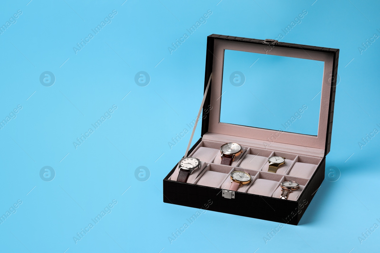 Photo of Jewelry box with many different wristwatches on light blue background, space for text