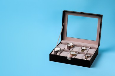 Jewelry box with many different wristwatches on light blue background, space for text