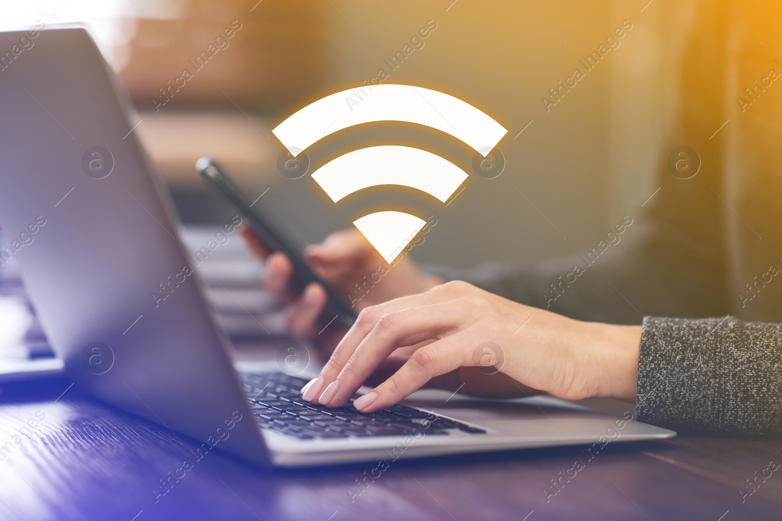 Image of Woman using smartphone and laptop connected to WiFi at wooden table indoors, closeup