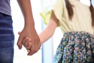 Children holding hands on blurred background, closeup. Unity concept