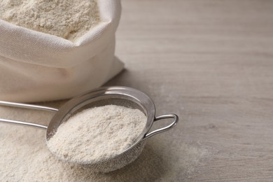 Sieve with quinoa flour on wooden table. Space for text