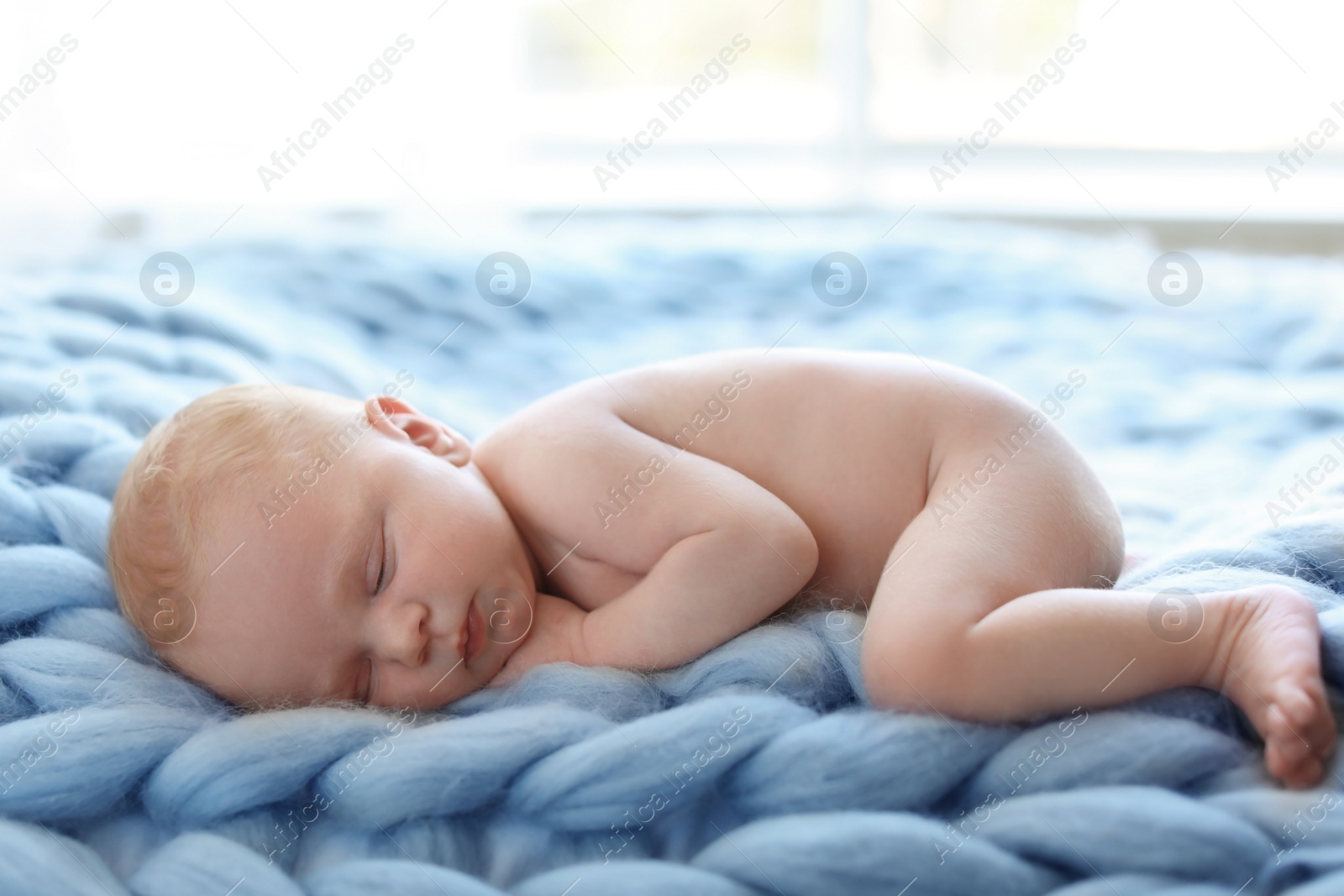 Photo of Adorable newborn baby lying on knitted blanket indoors