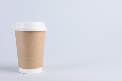 Photo of Paper cup with plastic lid on light background, space for text. Coffee to go