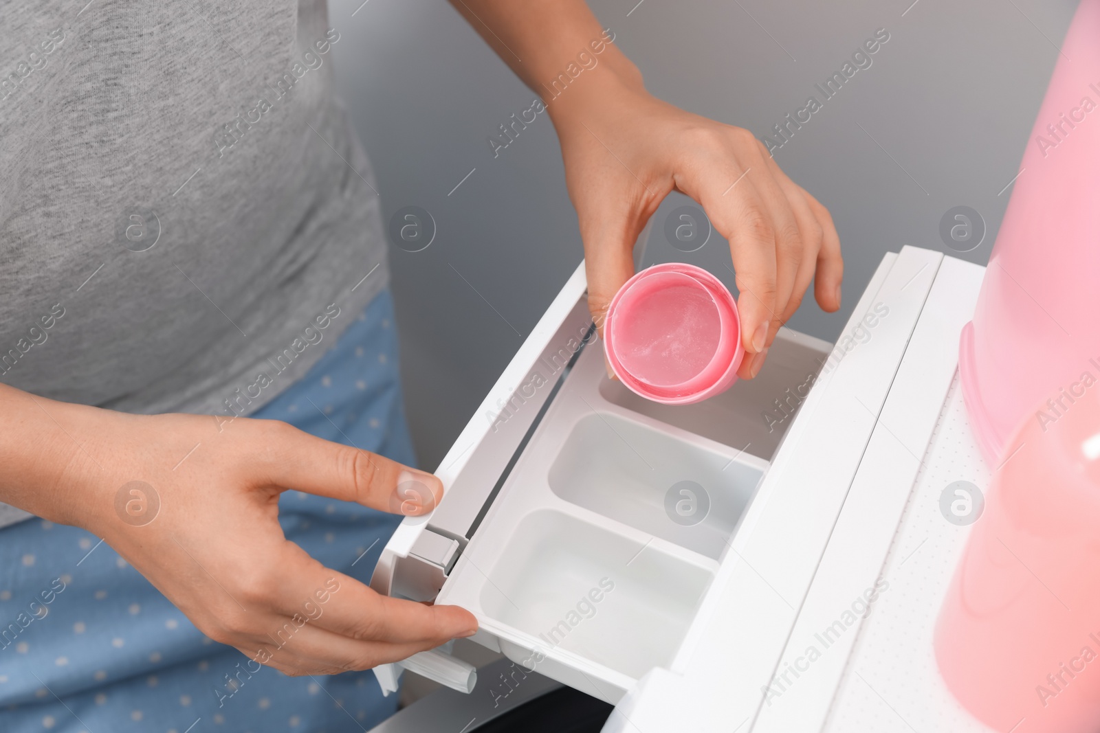 Photo of Woman pouring laundry detergent into drawer of washing machine, closeup