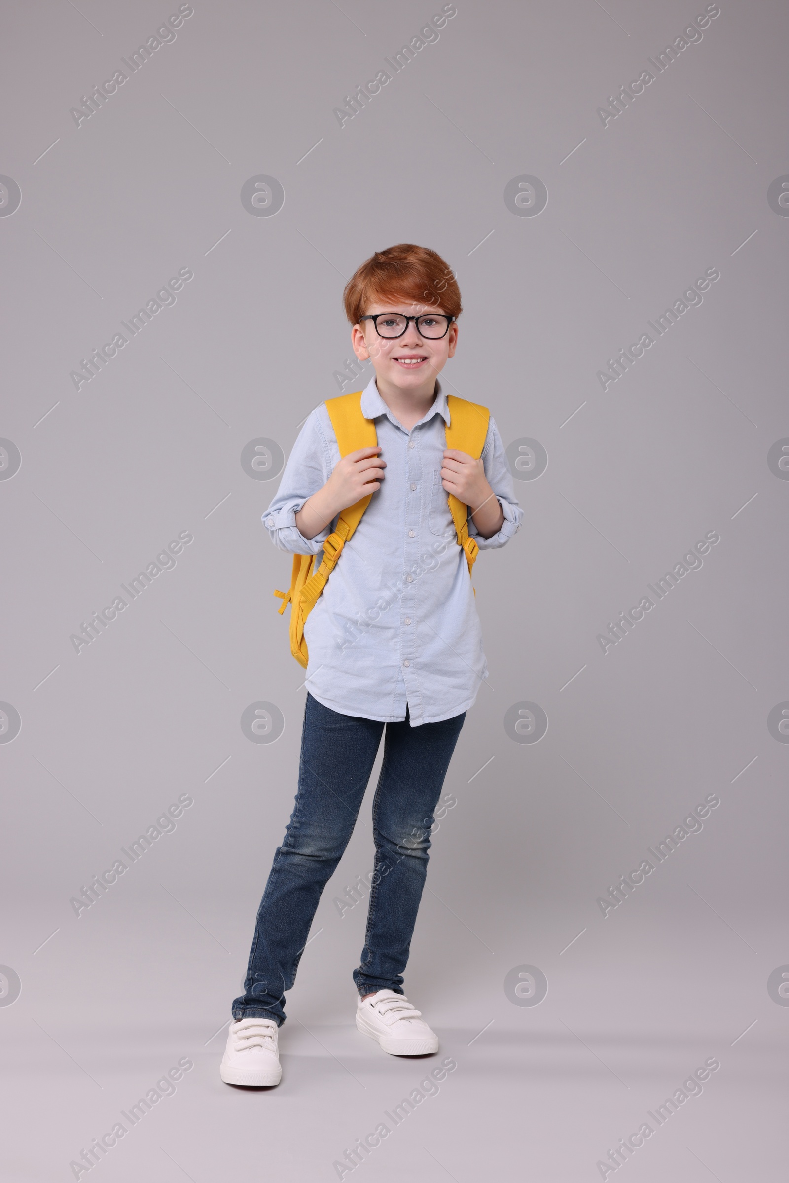 Photo of Happy schoolboy with backpack on grey background