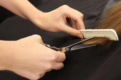 Photo of Professional hairdresser cutting woman's hair, closeup view