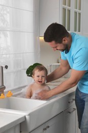 Photo of Father washing his little baby in sink at home