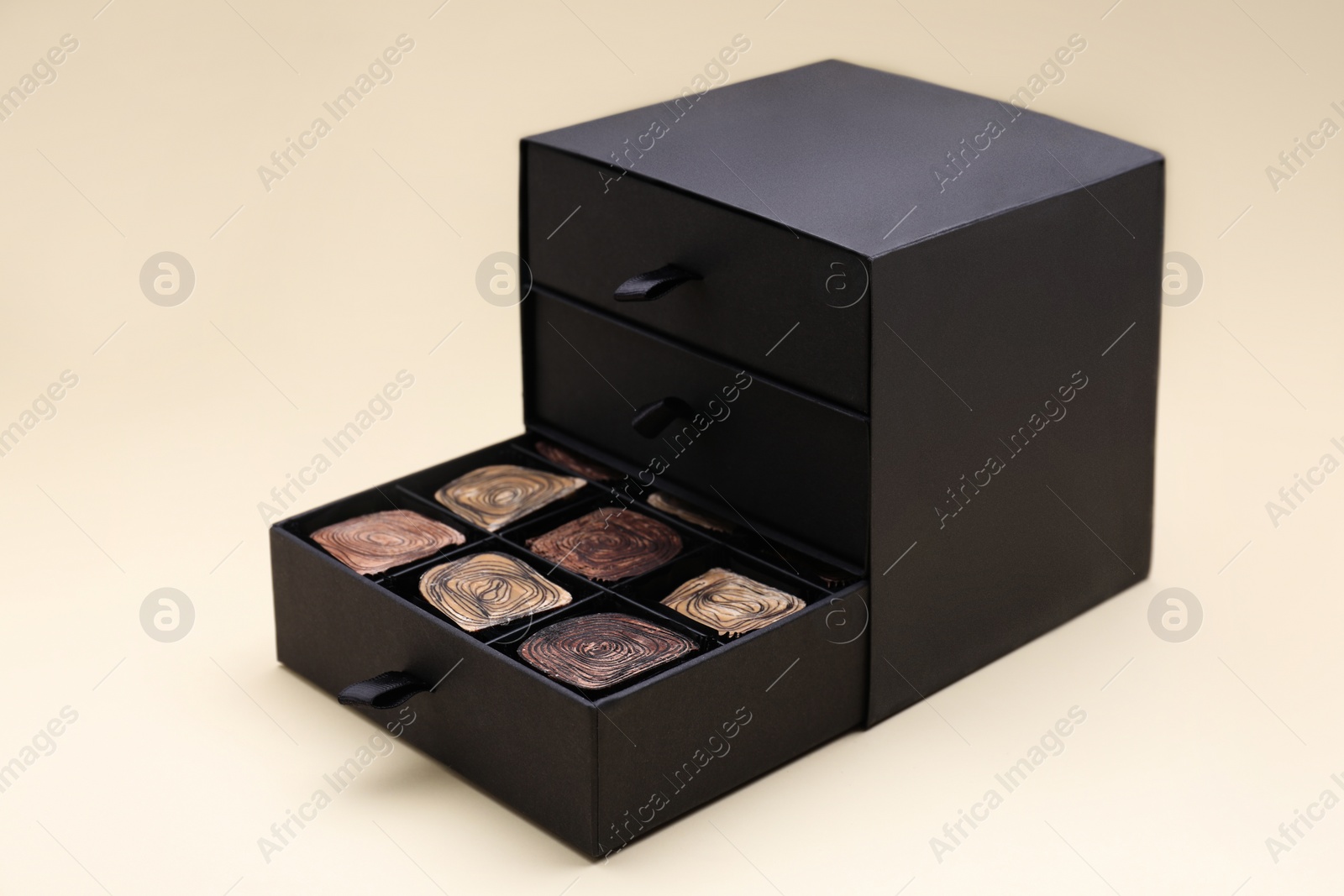 Photo of Box of tasty chocolate candies on beige background