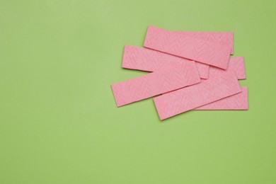 Many sticks of tasty chewing gum on light green background, flat lay. Space for text