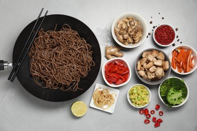 Photo of Wok with noodles, chicken and other products on light grey table, flat lay