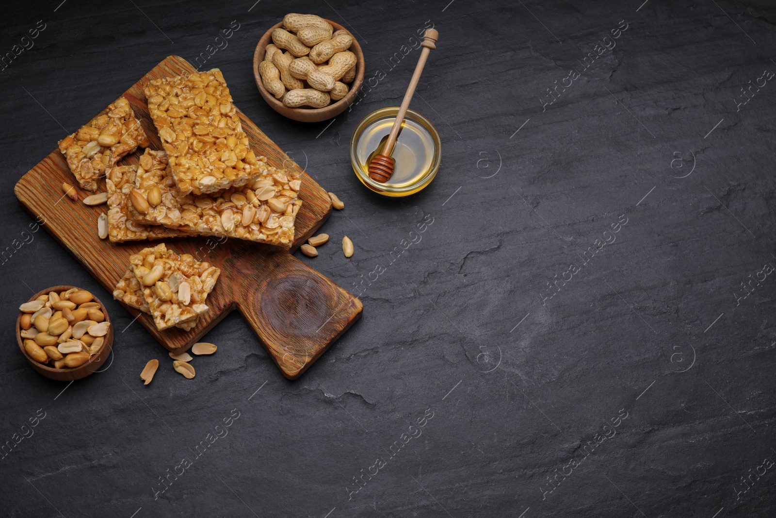 Photo of Delicious peanut bars (kozinaki) and ingredients on black table, flat lay. Space for text