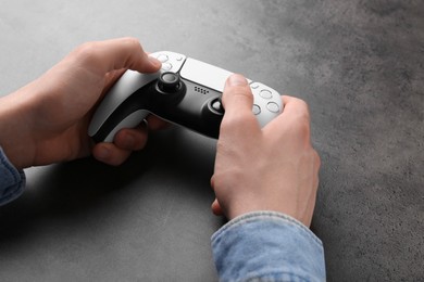 Man using wireless game controller at grey table, closeup