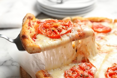 Photo of Taking slice of hot cheese pizza Margherita on table, closeup
