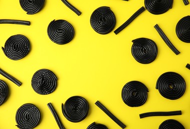 Tasty liquorice candies on yellow background, flat lay. Space for text