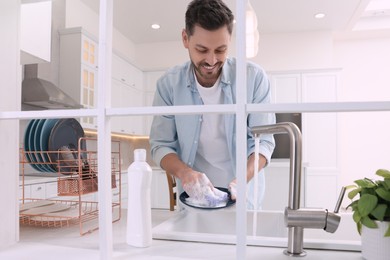 Photo of Man washing plate above sink in kitchen, view from outside