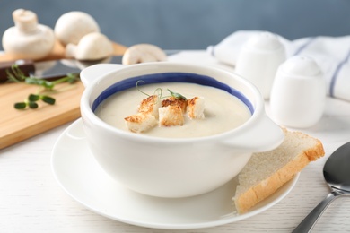 Delicious cream soup with croutons on white wooden table