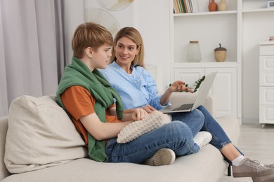 Happy teenage son and his mother with laptop at home